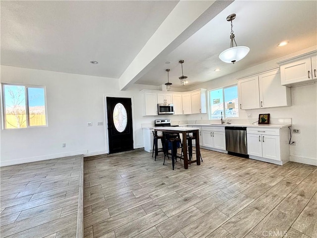 kitchen with stainless steel appliances, wood finish floors, light countertops, and baseboards