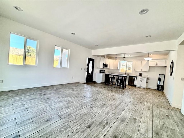 unfurnished living room with wood finish floors, baseboards, and recessed lighting