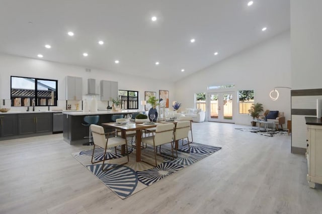 dining area featuring french doors, sink, light hardwood / wood-style floors, and high vaulted ceiling