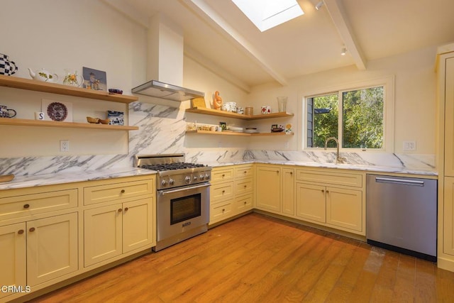 kitchen with a skylight, light wood-type flooring, island exhaust hood, stainless steel appliances, and decorative backsplash