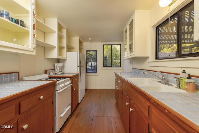 kitchen featuring dark hardwood / wood-style floors, white appliances, tile countertops, and sink