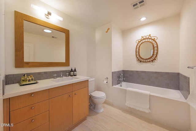 bathroom featuring tasteful backsplash, a tub to relax in, hardwood / wood-style flooring, vanity, and toilet