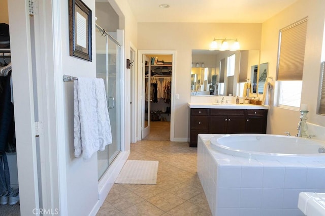 full bathroom featuring a shower stall, a walk in closet, vanity, and a bath