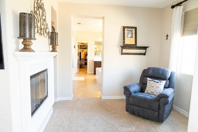 living area with light carpet, baseboards, and a glass covered fireplace