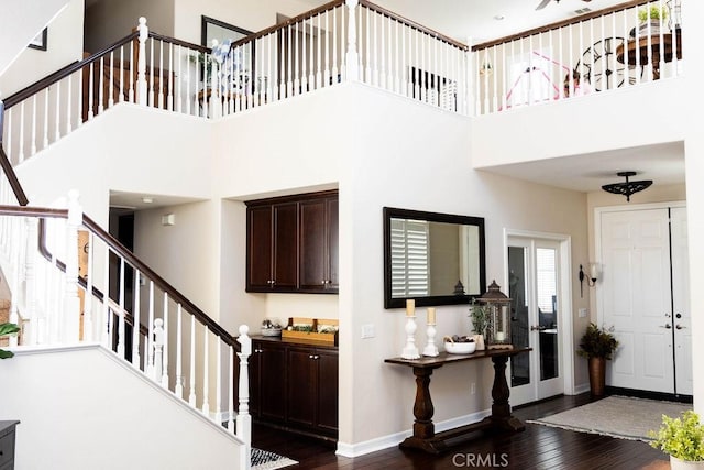 foyer entrance featuring a high ceiling, dark wood-type flooring, stairway, and baseboards