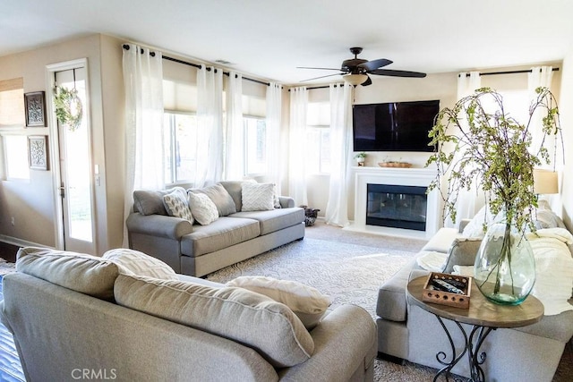 carpeted living area with ceiling fan and a glass covered fireplace