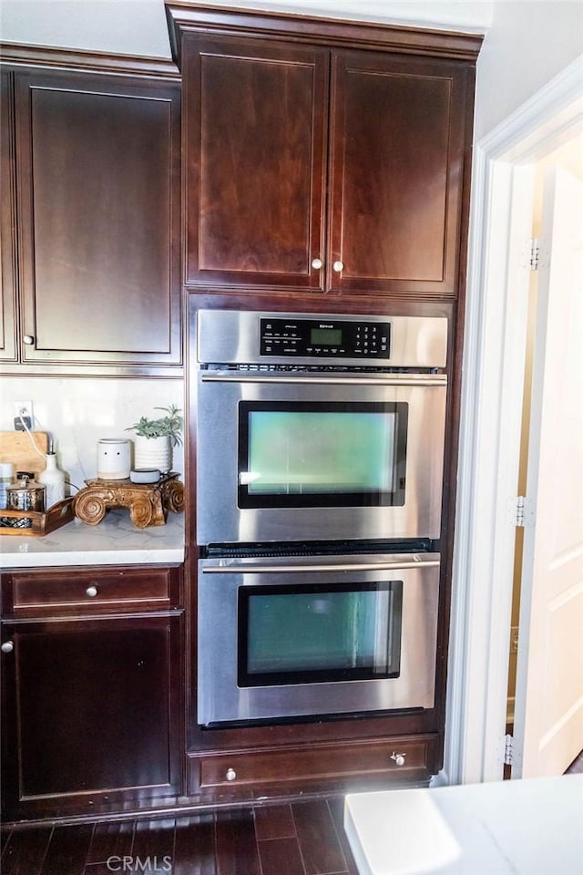 kitchen featuring light countertops, stainless steel double oven, and dark brown cabinets