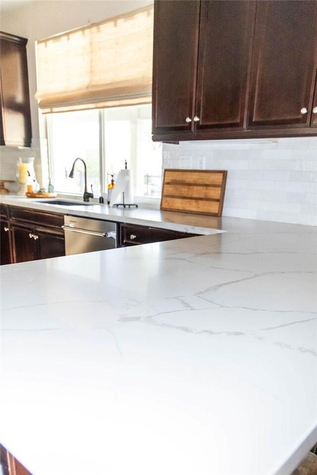 kitchen with tasteful backsplash, sink, stainless steel dishwasher, and light stone counters