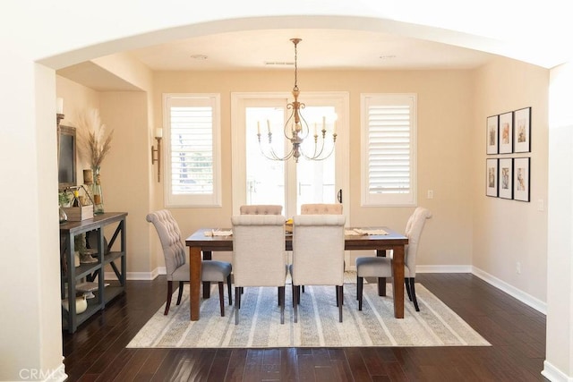 dining room with an inviting chandelier, baseboards, arched walkways, visible vents, and wood finished floors