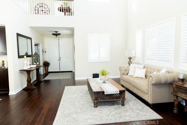 living room with dark hardwood / wood-style flooring and a towering ceiling