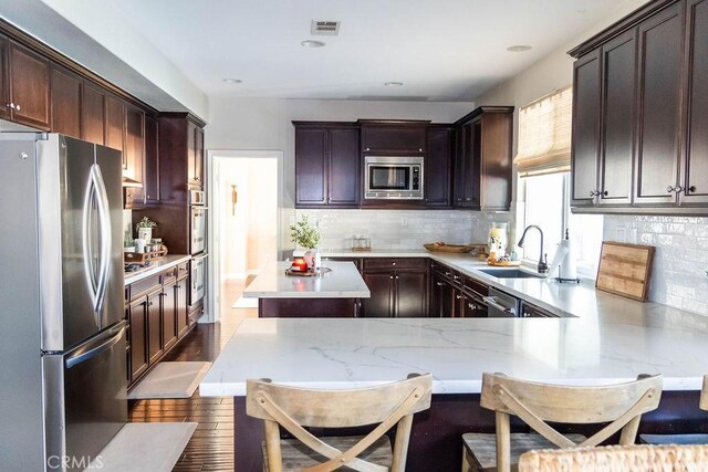 kitchen with appliances with stainless steel finishes, sink, a breakfast bar area, and kitchen peninsula