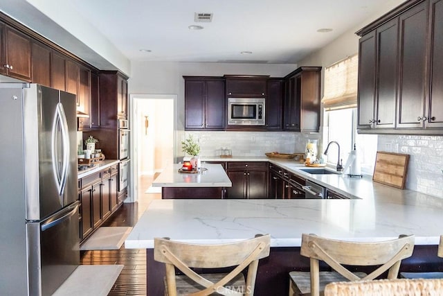 kitchen with a sink, stainless steel appliances, dark brown cabinetry, and visible vents