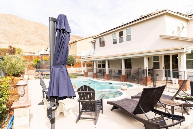 view of pool featuring a patio, a mountain view, and an in ground hot tub