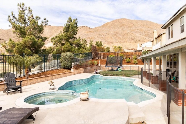 view of swimming pool with a trampoline, a fenced backyard, a mountain view, and a patio