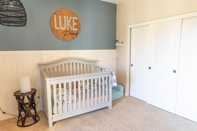 bedroom with a nursery area, carpet, and a closet