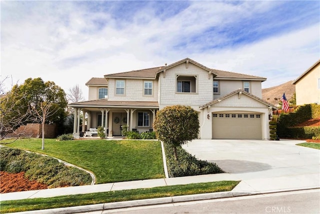 view of front of house featuring stucco siding, an attached garage, driveway, a front lawn, and covered porch