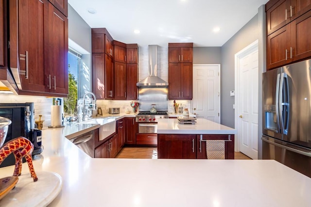 kitchen featuring tasteful backsplash, appliances with stainless steel finishes, sink, and wall chimney range hood