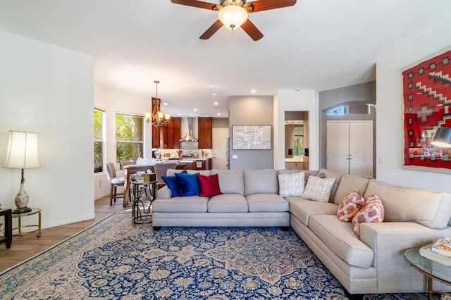 living room featuring ceiling fan with notable chandelier and light hardwood / wood-style flooring