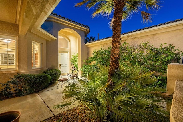 exterior entry at twilight featuring a patio area