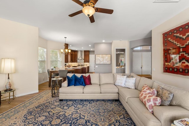 living room with hardwood / wood-style floors and ceiling fan with notable chandelier