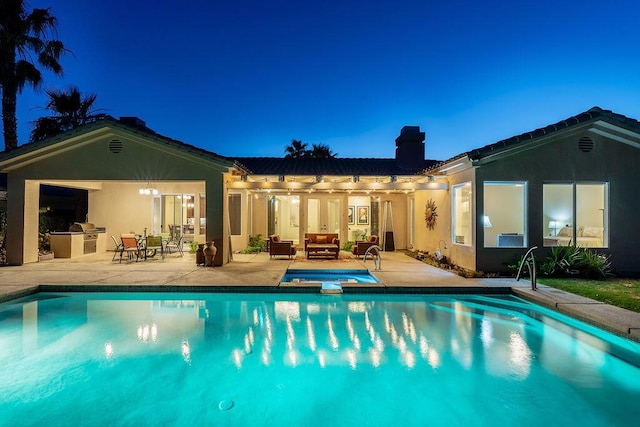 back of house featuring a swimming pool with hot tub, exterior kitchen, and a patio