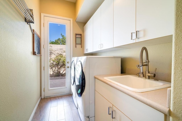 washroom with cabinets, sink, light hardwood / wood-style floors, and washer and dryer