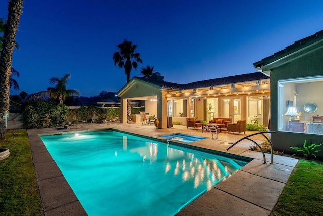 pool at twilight with an in ground hot tub, outdoor lounge area, and a patio