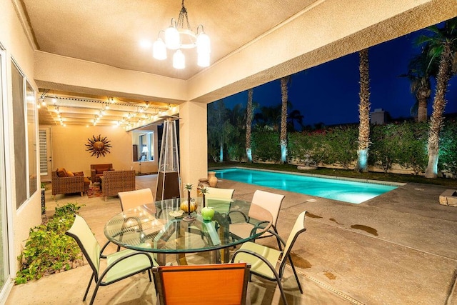 pool at night featuring a patio area and outdoor lounge area