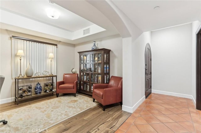 sitting room with hardwood / wood-style flooring and a raised ceiling