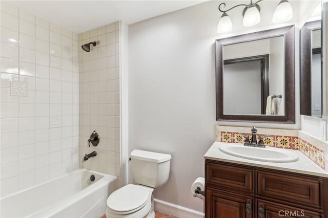 full bathroom featuring tiled shower / bath, vanity, and toilet