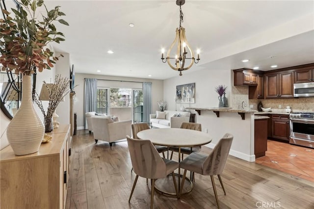 dining room featuring an inviting chandelier, sink, and light hardwood / wood-style floors