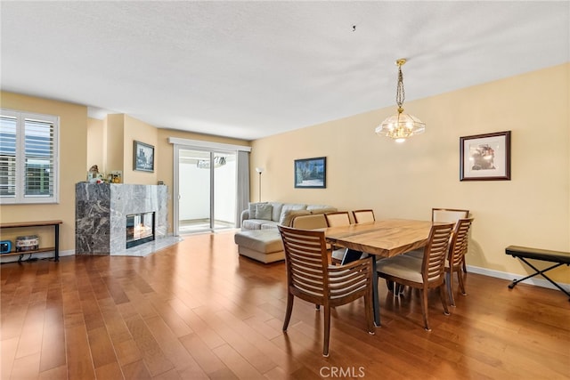 dining space featuring an inviting chandelier, a premium fireplace, and hardwood / wood-style floors