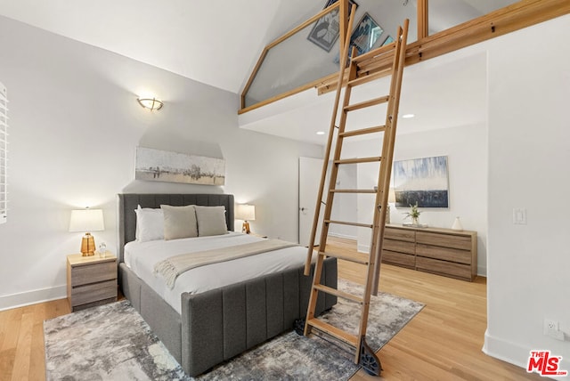 bedroom featuring wood-type flooring and high vaulted ceiling