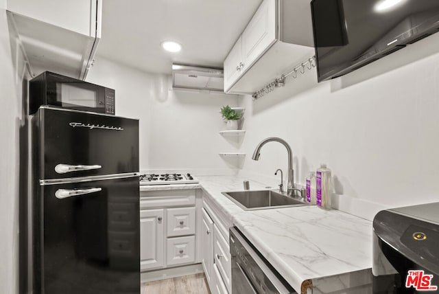 kitchen featuring sink, black appliances, light hardwood / wood-style floors, white cabinets, and light stone countertops