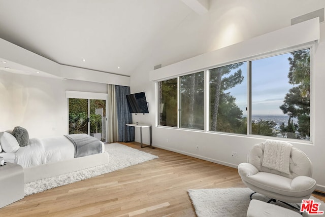 bedroom featuring light hardwood / wood-style flooring and vaulted ceiling with beams