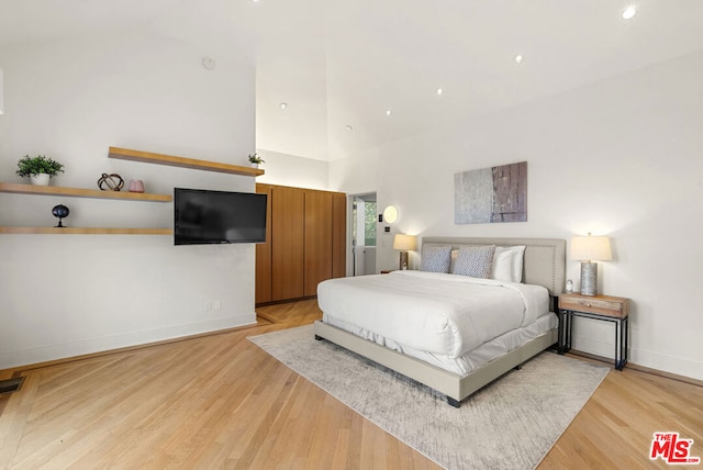 bedroom featuring high vaulted ceiling and light hardwood / wood-style floors