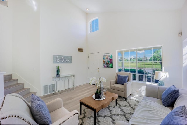 living room with a towering ceiling, a wealth of natural light, and light hardwood / wood-style flooring