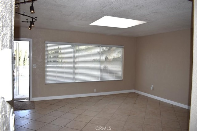 spare room with light tile patterned floors, a textured ceiling, and a skylight