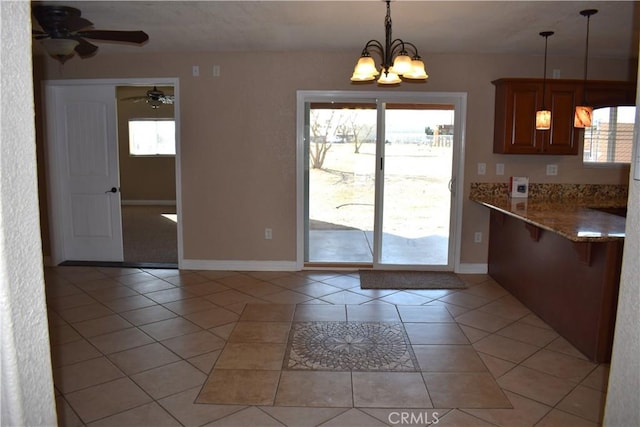 unfurnished dining area featuring ceiling fan with notable chandelier and light tile patterned flooring