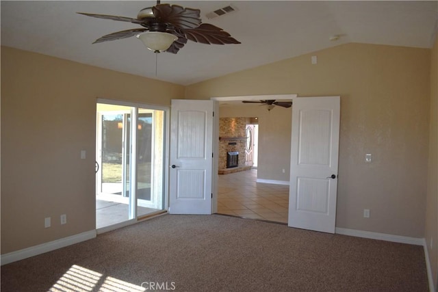 carpeted spare room with lofted ceiling, a fireplace, and ceiling fan