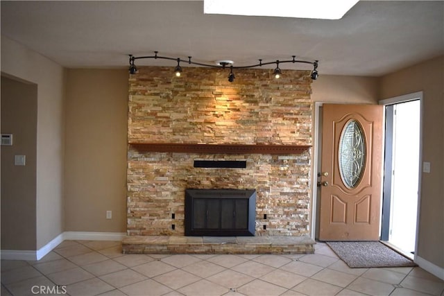 unfurnished living room featuring a stone fireplace, track lighting, and light tile patterned flooring