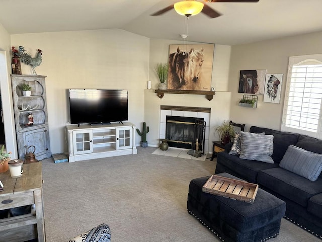 living room featuring ceiling fan, lofted ceiling, light carpet, and a tile fireplace