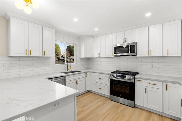 kitchen with appliances with stainless steel finishes, tasteful backsplash, sink, white cabinets, and light stone countertops