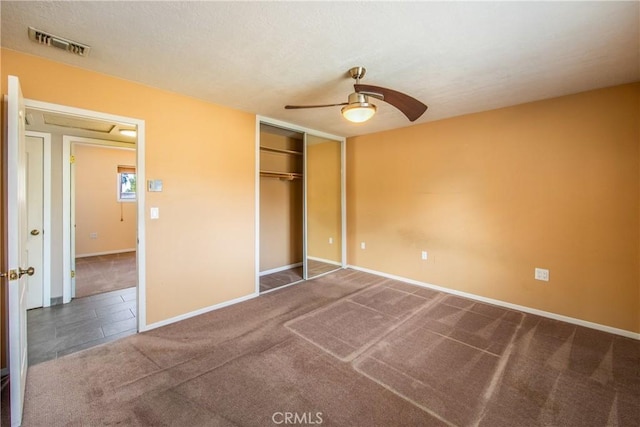 unfurnished bedroom featuring dark carpet, a closet, and ceiling fan