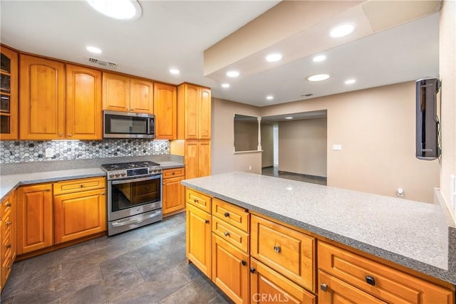 kitchen featuring light stone counters, stainless steel appliances, and backsplash