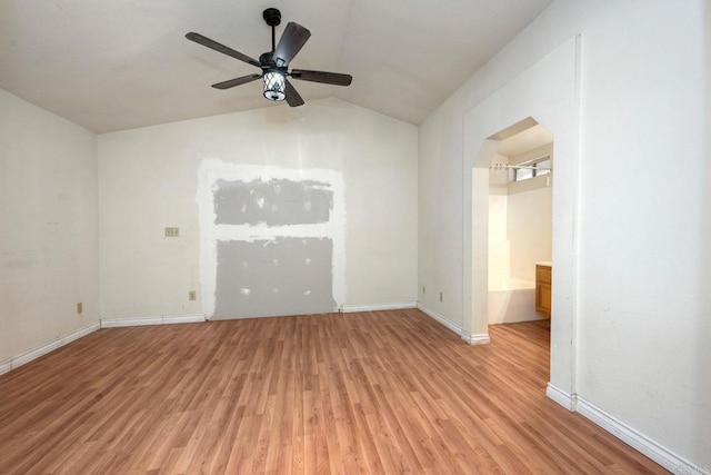 spare room with ceiling fan, vaulted ceiling, and light wood-type flooring