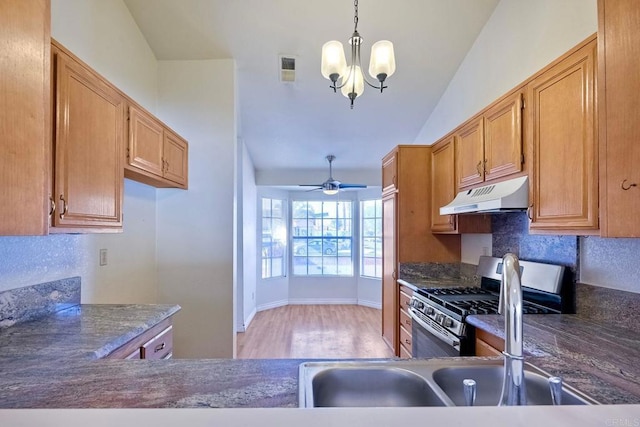 kitchen featuring sink, vaulted ceiling, hanging light fixtures, stainless steel range with gas cooktop, and ceiling fan with notable chandelier