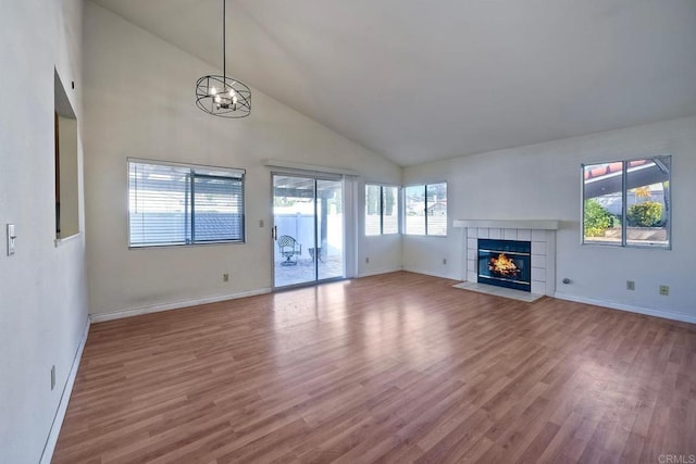 unfurnished living room featuring wood-type flooring, high vaulted ceiling, an inviting chandelier, and a fireplace