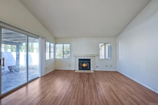 unfurnished living room with a fireplace, wood-type flooring, and vaulted ceiling