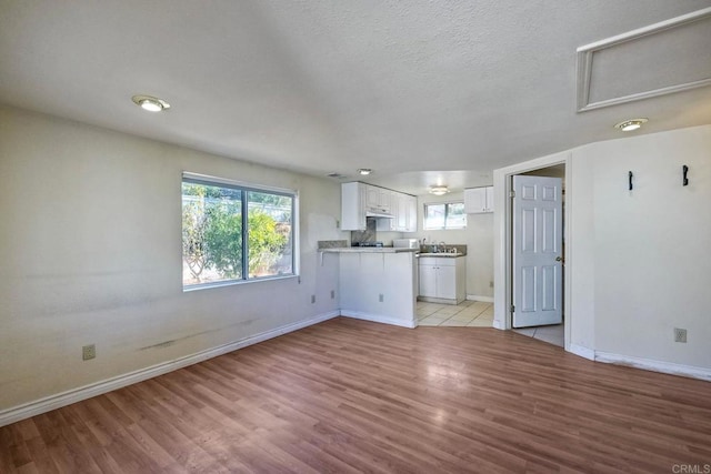 unfurnished living room featuring sink, a textured ceiling, and light wood-type flooring